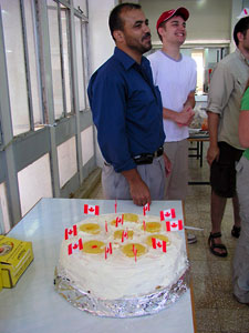 Mohammad Ahmuru, the cook, standing next to the cake he baked for Canada Day (photo by Katie Van Petten)