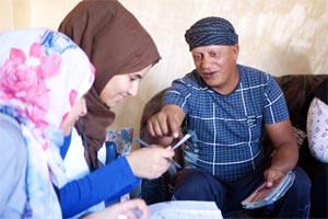 Abu Issa shares stories and photographs with CEPU translators Amira Eneizat and Eslam AlDawdieh during an interview session at his house in Bunayat. 